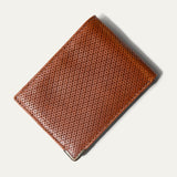 The ginger diamond-perforated Mogul Billfold open with cash and credit cards tucked into the slots, including an American Express and Delta SkyMiles card.