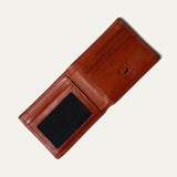 Amber/cognac leather billfold wallet open, showing card slots, embossed WILL Leather Goods logo, and a clear ID window, on a white background.