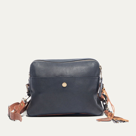 Black leather crossbody bag with cognac strap, front view, with zip top, snap front pocket, and fringe tassel zipper pull