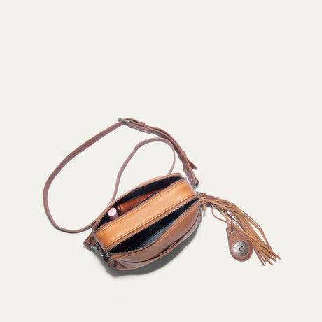 Top-down view of the tan leather crossbody bag unzipped, showing lipstick and a phone inside with plaid fabric lining
