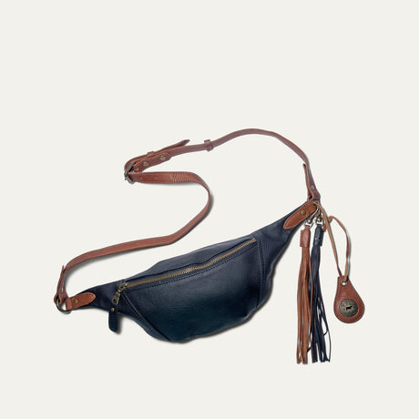 Will Leather Goods black and cognac two-tone leather fanny pack with fringe tassel charm, flat lay with adjustable strap