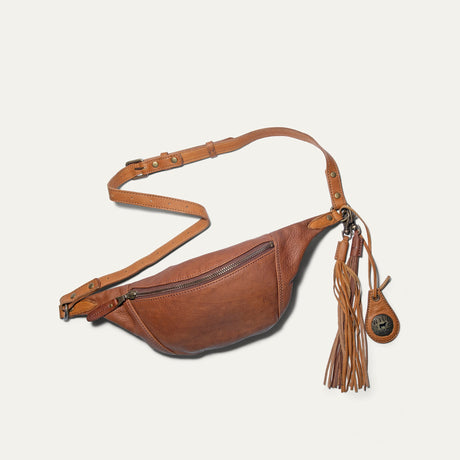 Will Leather Goods cognac and tan two-tone leather fanny pack with fringe tassel charm, flat lay with adjustable strap
