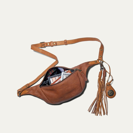 Cognac and tan leather fanny pack unzipped, showing makeup, a wallet, and cash inside