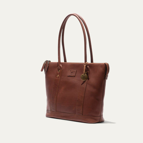 Dark cognac pebbled leather zip tote, three-quarter angle view showing the side gusset and zipper