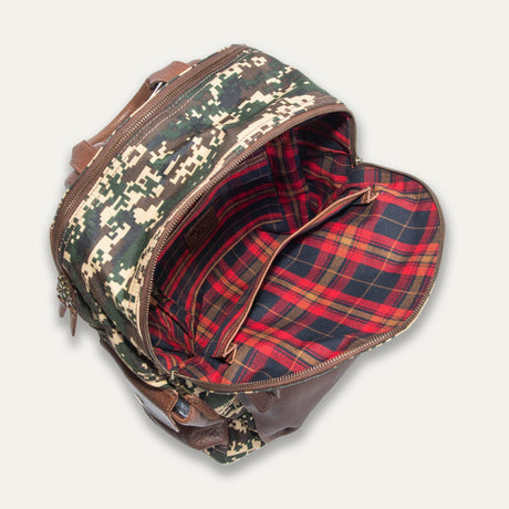 Overhead view into the open green digital camo Canvas + Leather Backpack, showing the red and navy plaid interior lining and zip pocket.