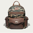 Will Leather Goods Canvas + Leather Backpack in green digital camo canvas with brown leather trim, front view showing the zip front pocket, flap pocket with turn-lock closure, and two side pockets, on a white background.