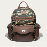 Will Leather Goods Canvas + Leather Backpack in green digital camo canvas with brown leather trim, front view showing the zip front pocket, flap pocket with turn-lock closure, and two side pockets, on a white background.
