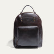 Dark brown leather round-top backpack with a top handle, front zip pocket, and embossed Will Leather Goods patch, front view.