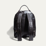 Back view of the dark brown leather backpack showing the top handle and two adjustable shoulder straps.