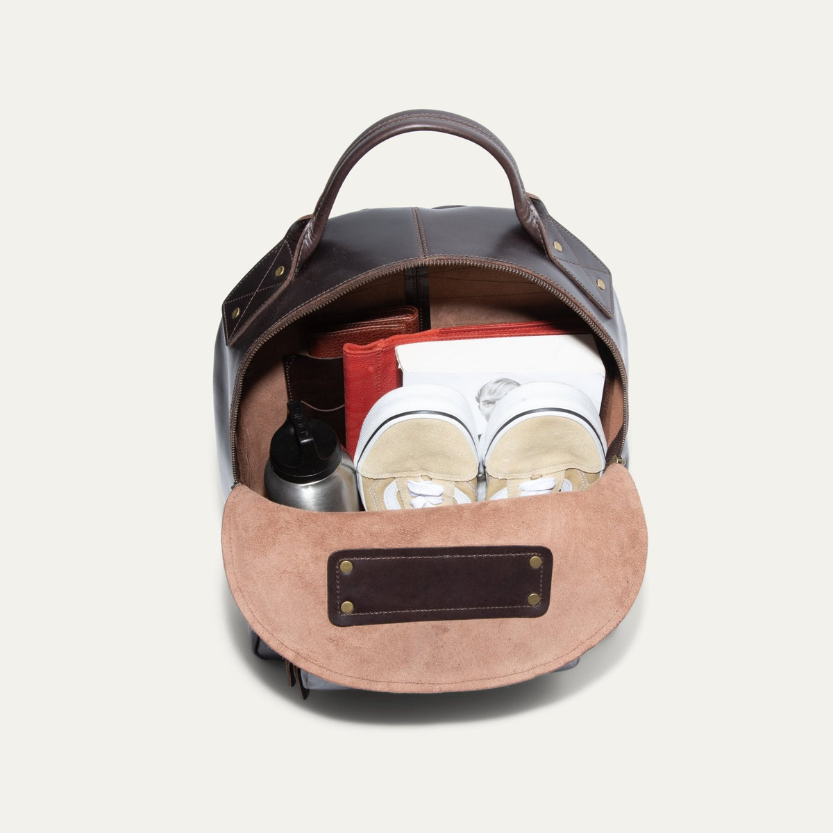 Interior view of the dark brown leather backpack open, showing the suede-lined main compartment and interior slip pocket.