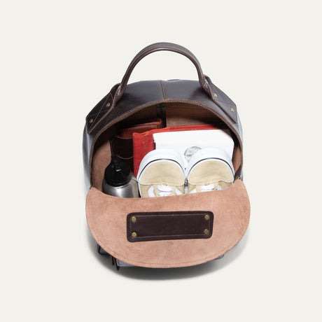 Interior view of the dark brown leather backpack open, showing the suede-lined main compartment and interior slip pocket.
