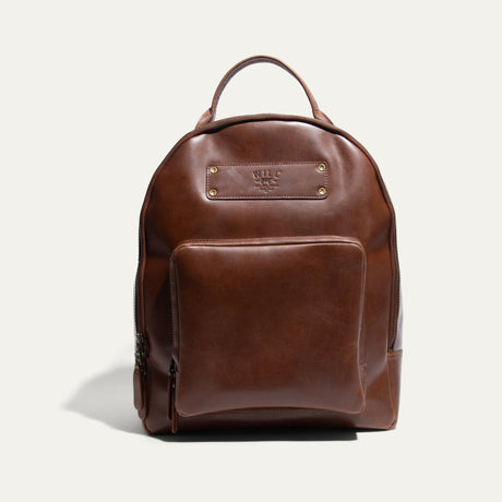 Tan leather round-top backpack with a top handle, front zip pocket, and embossed Will Leather Goods patch, front view.