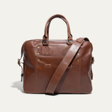Tan leather briefcase, front pocket view, with zip top, snap-top front pocket, and adjustable shoulder strap