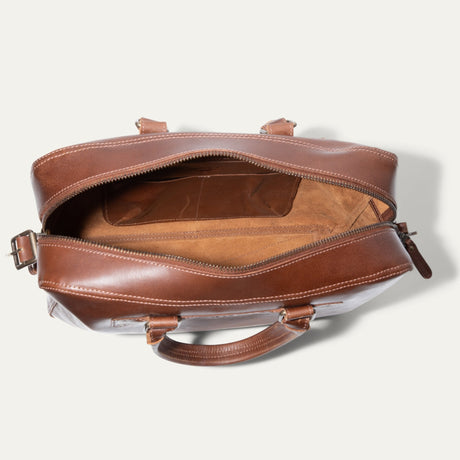 Top-down view of the tan leather briefcase open, showing the interior organizer pocket and suede lining