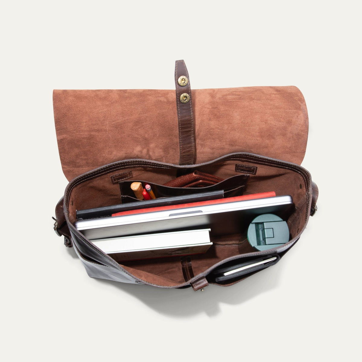 Will Leather Goods Field Messenger bag in dark brown leather, opened flat and packed with a laptop, notebooks, pens, a wallet, and a round travel case inside the suede-lined interior.