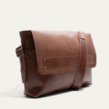 Will Leather Goods Field Messenger bag in tan leather, three-quarter angled view showing the buckled shoulder strap and embossed WILL logo strip.