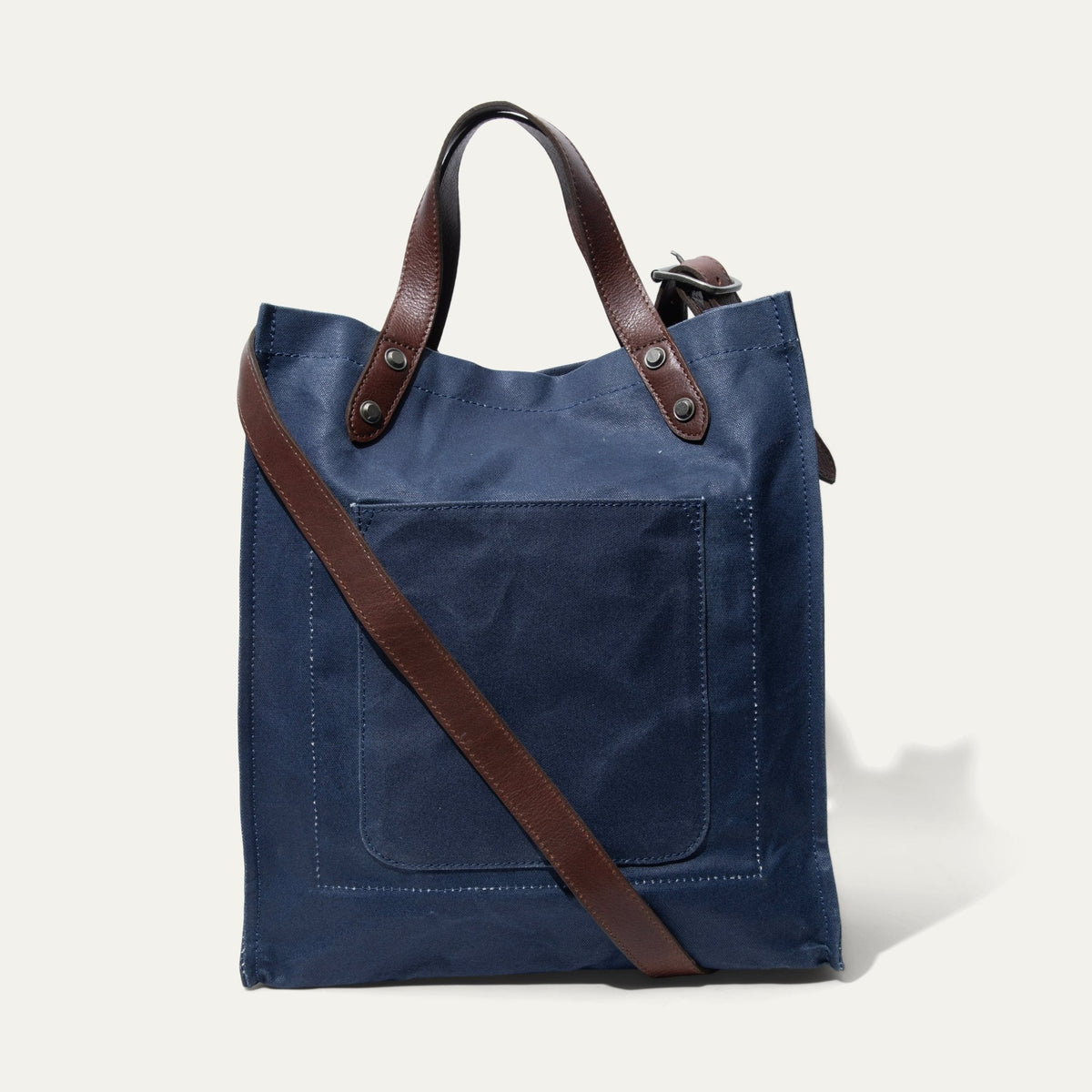 Navy waxed canvas market tote shown straight-on in a smaller framing, highlighting the front zip pocket and diagonal crossbody strap