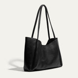 Side angle of the black Workshop Tote showing its pebbled leather texture, tall curved handles, and embossed Will Leather Goods logo.
