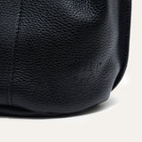 Extreme close-up of the black leather bucket bag's embossed Will Leather Goods logo and pebbled texture