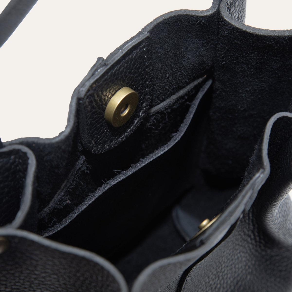 Close-up of the black leather bucket bag's base showing the embossed Will Leather Goods logo