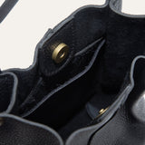 Close-up of the black leather bucket bag's base showing the embossed Will Leather Goods logo