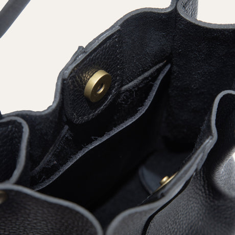 Close-up of the black leather bucket bag's base showing the embossed Will Leather Goods logo