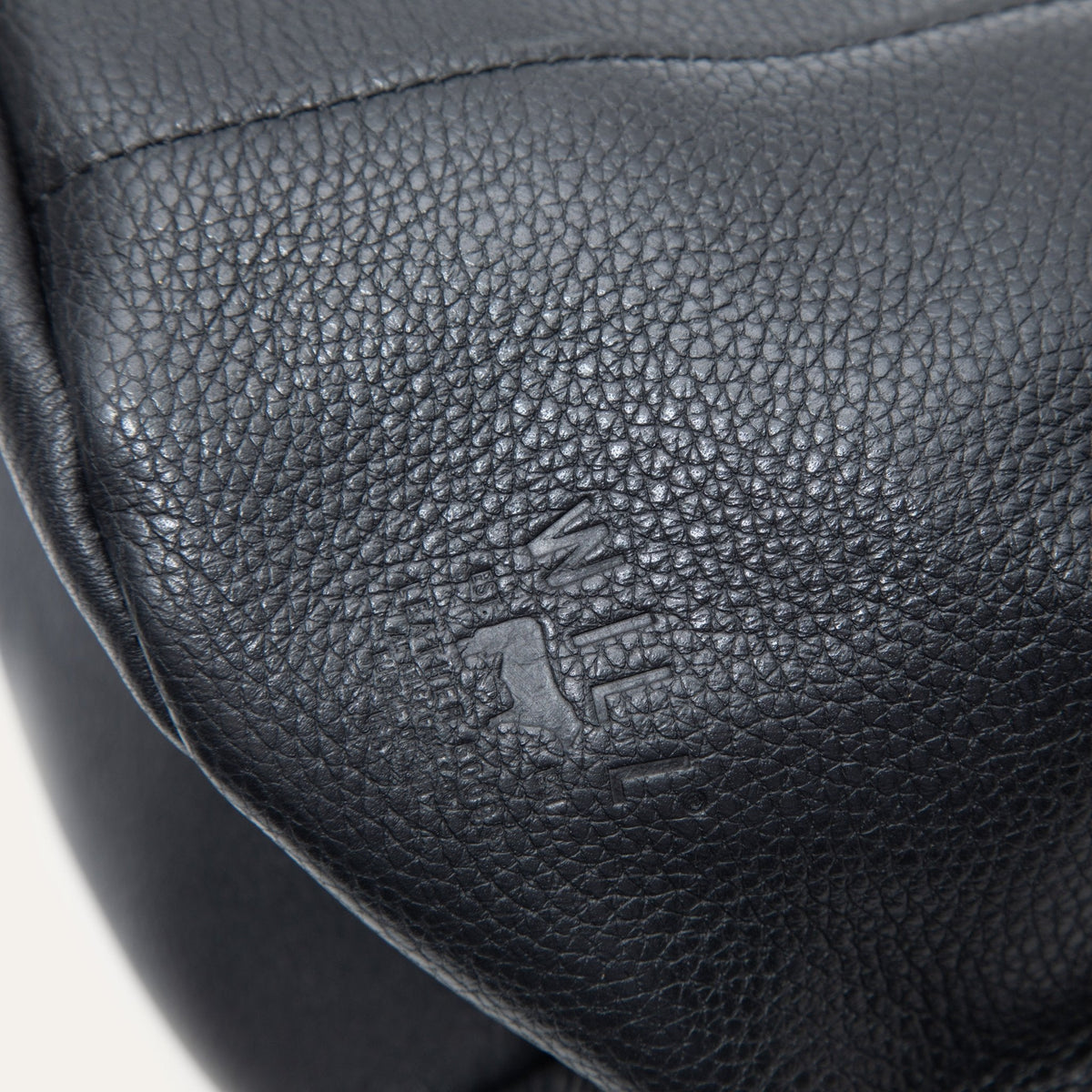 Macro close-up of the black leather bucket bag's embossed Will Leather Goods logo