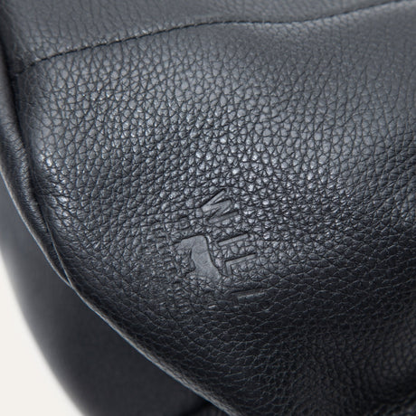 Macro close-up of the black leather bucket bag's embossed Will Leather Goods logo
