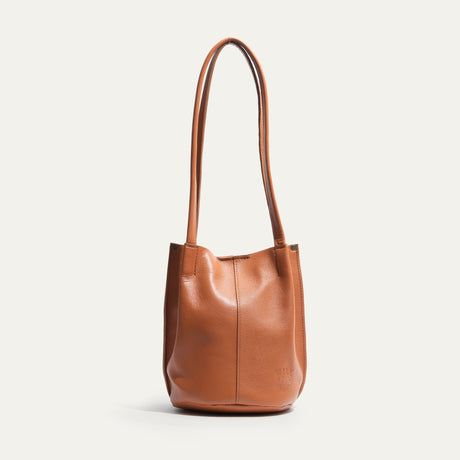 Caramel leather bucket bag, side profile view showing the rounded gusset