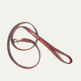 Will Leather Goods cognac leather dog leash coiled on a white background, showing the brass clasp