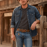 Lifestyle photo of a man in a denim western shirt and jeans wearing the tan Baez Wild Ones Belt with its studded, tooled leather and antiqued double-prong buckle.