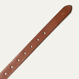 Close-up diagonal view of the tapered tip end of the cognac leather Bridal Belt, showing the embossed cow-head logo and row of sizing holes.