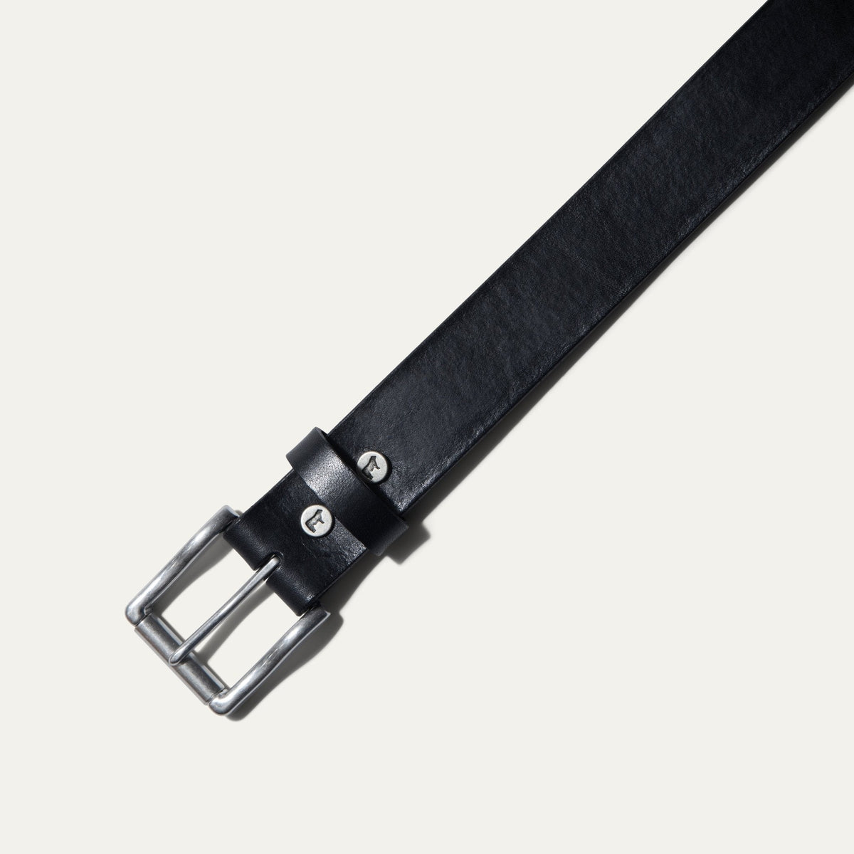 Close-up of the black leather belt's brushed nickel buckle and keeper loop with cattle snaps