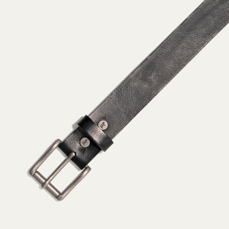 Close-up diagonal view of the black leather Bridal Belt's antique silver roller buckle, sizing holes, and embossed cow-head rivets on the keeper loop.