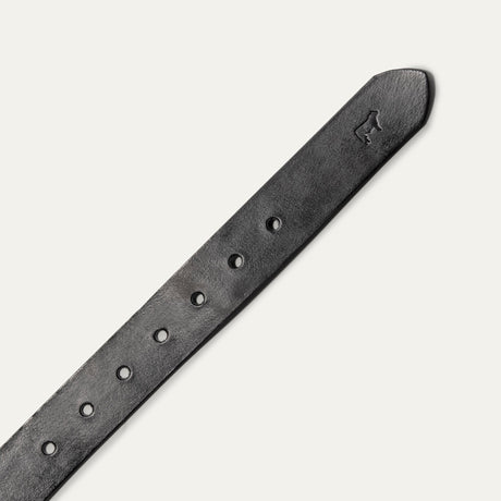 Close-up diagonal view of the tapered tip end of the black leather Bridal Belt, showing the embossed cow-head logo and row of sizing holes.