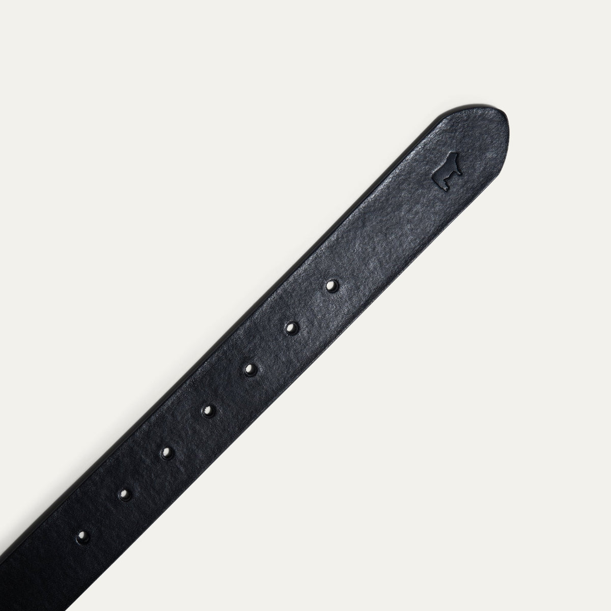 Close-up of the black leather belt's tip, showing the embossed cattle logo and adjustment holes