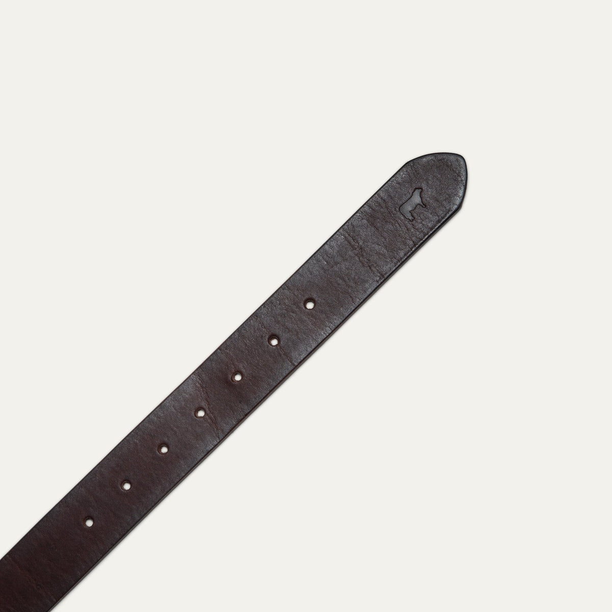 Close-up of the dark brown leather belt's tip, showing the embossed cattle logo and adjustment holes