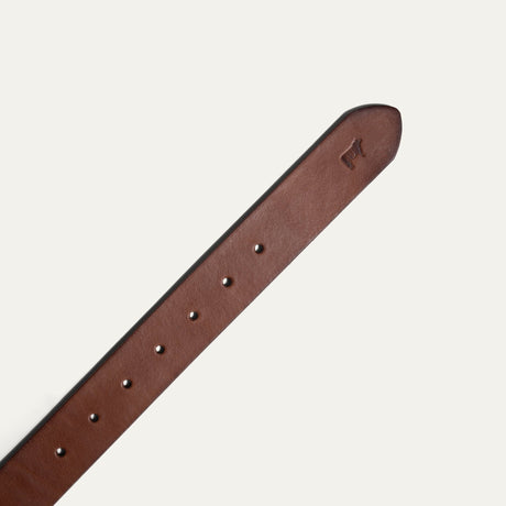 Close-up of the cognac leather belt's tip, showing the embossed cattle logo and adjustment holes