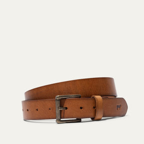 Will Leather Goods tan leather belt coiled, showing the antique brass roller buckle