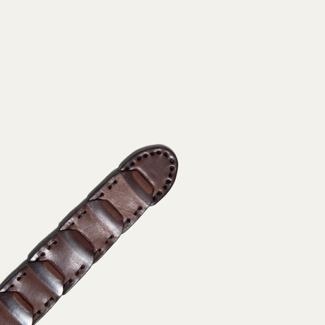 Close-up view of the tapered tip end of the brown leather Hand Laced Link Belt, showing the hand-laced rectangular link panels.