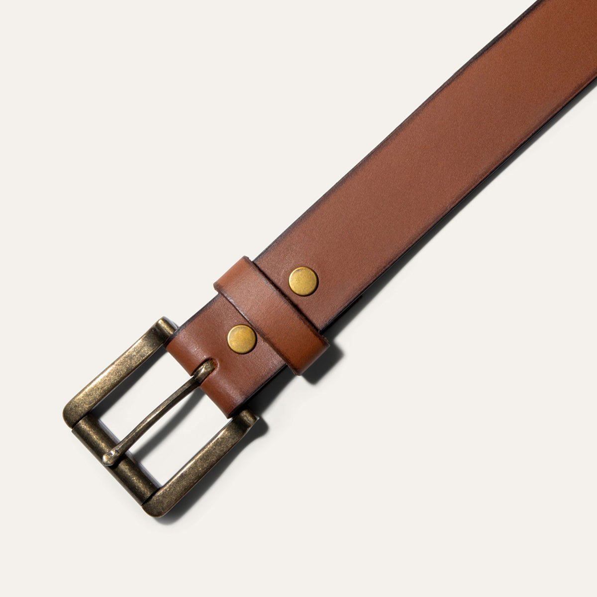 Close-up of the Black Edge Jean Belt strap in black leather, showing the black burnished edge, rivets, and row of adjustment holes near the rounded tip.