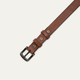 Close-up of cognac tan leather belt showing the double loop keepers with brass studs embossed with a cow logo.
