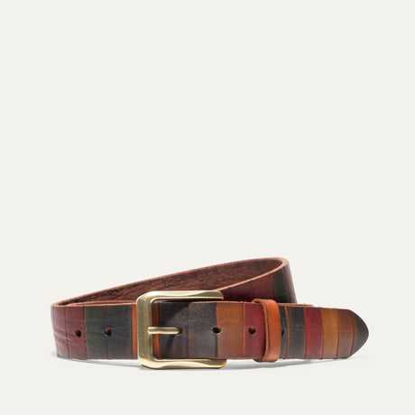 Will Leather Goods Hand Painted Color Block Belt coiled on a white background, showing hand-dyed leather panels in brown, rust, and navy with a brass roller buckle.