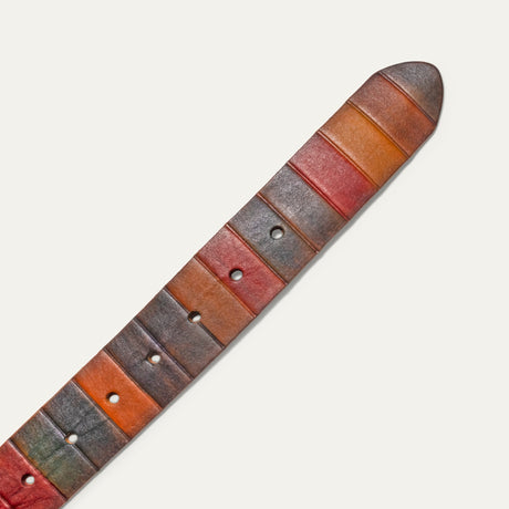 Close-up of the belt's rounded tip end, showing hand-painted leather panels in gray, rust, orange, and red with visible buckle holes.