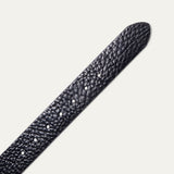 Close-up of the Shrunken American Bison Belt strap in black pebbled bison leather, showing the textured grain and row of adjustment holes near the rounded tip.