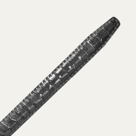 Close-up of the black Croco Belt's crocodile-embossed leather strap and adjustment holes, showing the deep glossy grain texture.