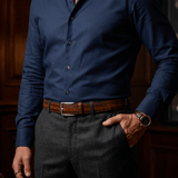Lifestyle photo of a man in a navy shirt and charcoal trousers wearing the cognac croco-embossed belt with a silver buckle, close-up at the waist.