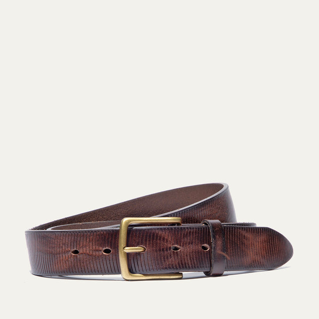 Dark brown leather belt coiled to show the brass buckle and fine embossed line texture running the length of the strap