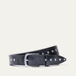Will Leather Goods Single Studded Belt in black leather, coiled flat showing the row of silver stud rivets along the edge and the brushed silver buckle, on a white background.