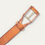 Close-up of the tan leather buckle belt's brass roller buckle and keeper loop, on a white background.